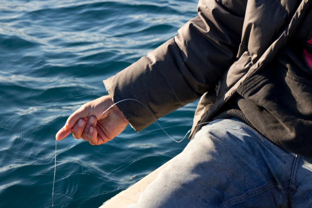a photo of an angler holding fishing line in hand to show that fishing line can cut you