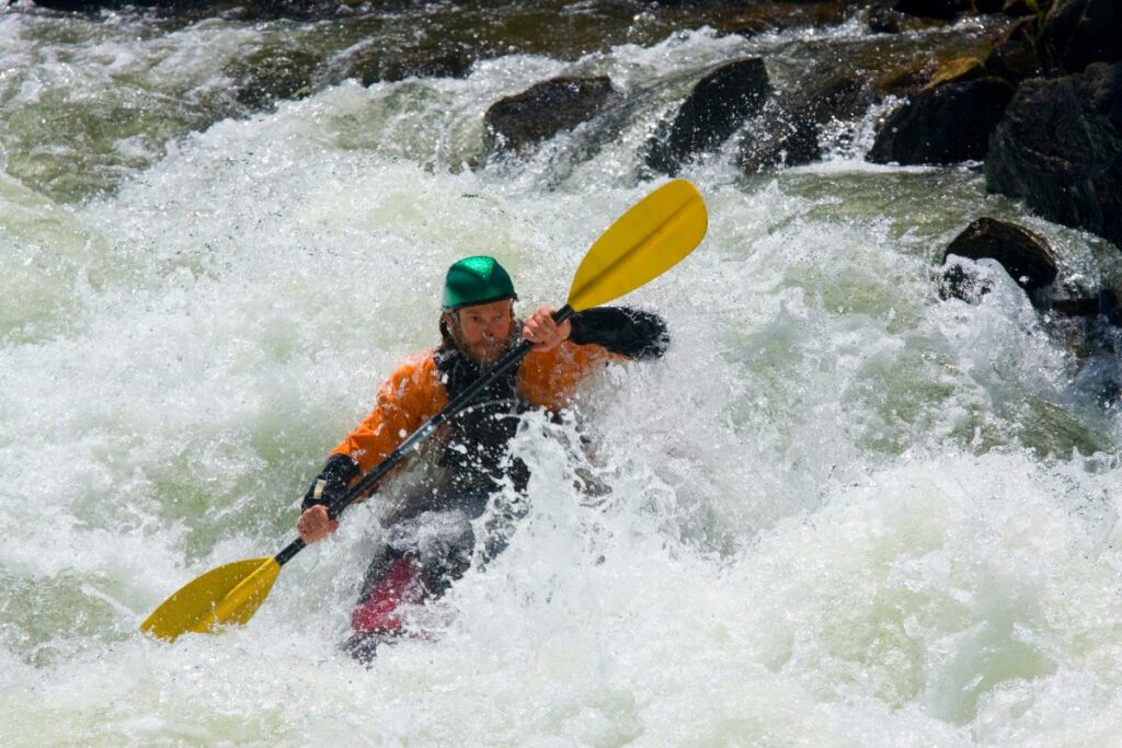 a photo of paddler kayaking in strong current to show what could go wrong kayaking