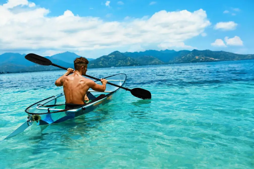 a photo of a muscular guy kayaking to answer does kayaking build muscles