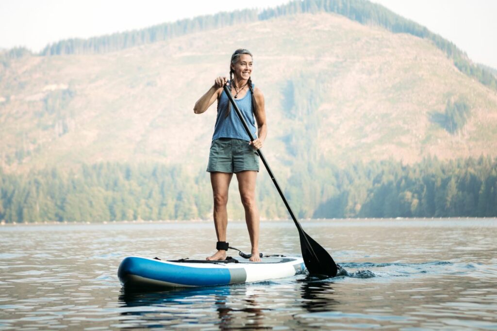 a photo of a woman paddle boarding to answer do you need to be able to swim to paddle board