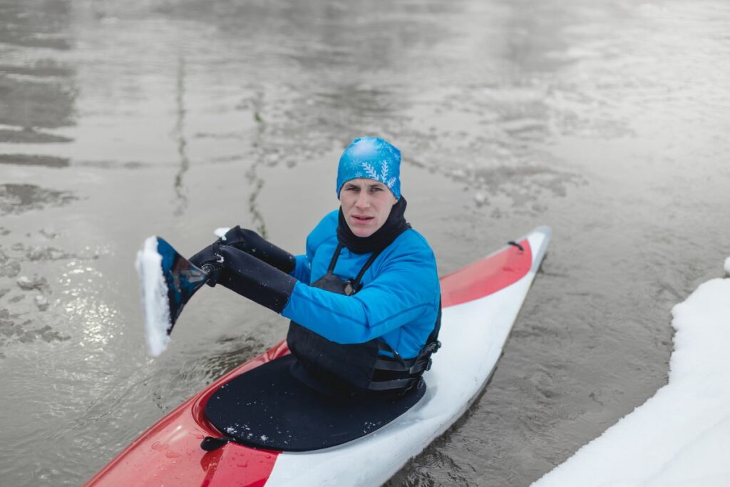 A photo of a kayaker paddling in snow to show when is it too cold too kayak