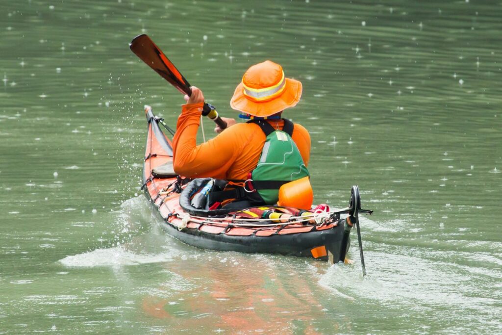 a photo of a man kayaking in the rain