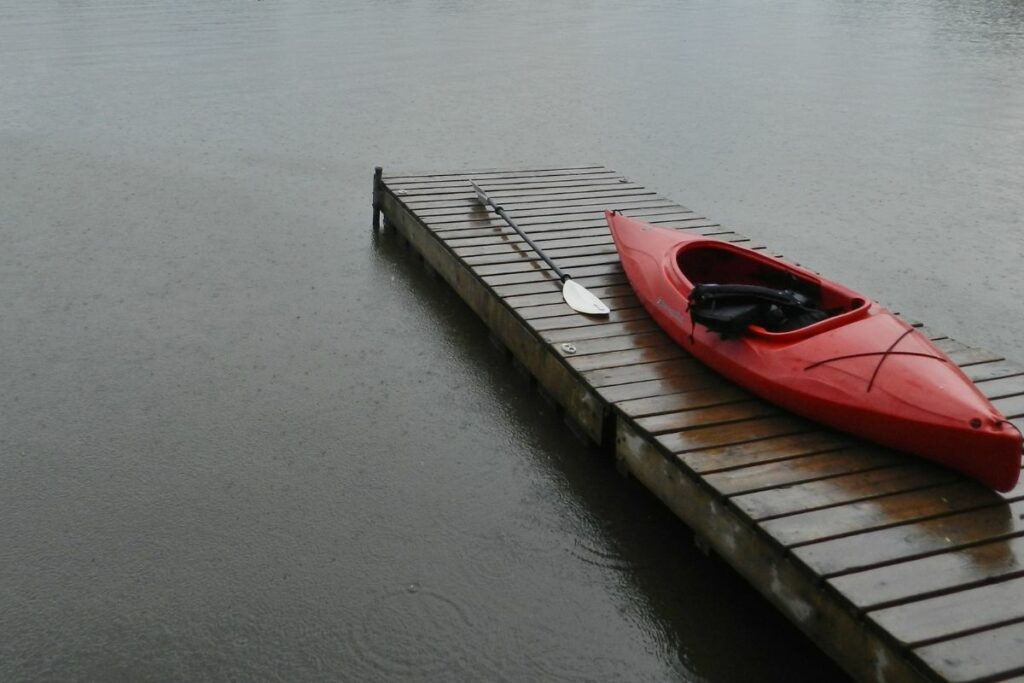 A photo of a kayak docked in the rain to answer can you kayak while it's raining